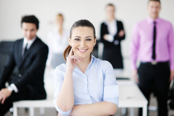 business woman standing with her staff in background