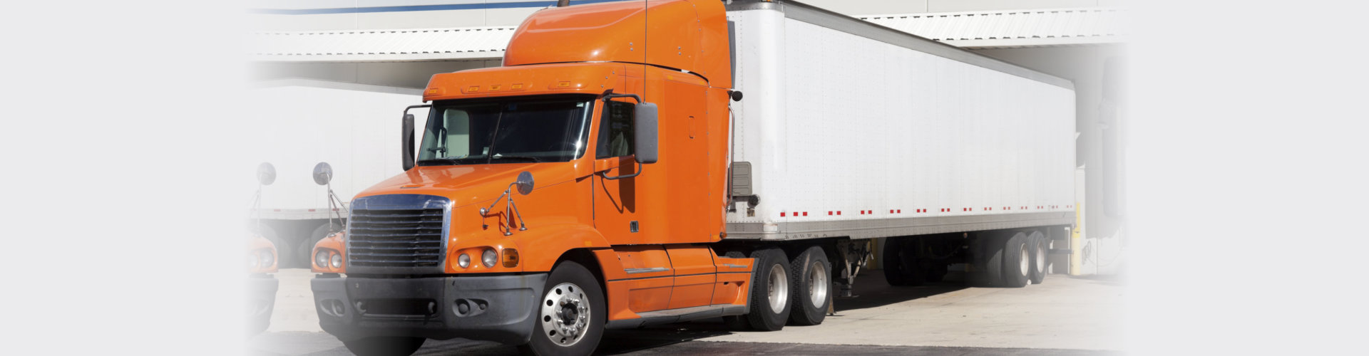 orange semi truck by the door of warehouse